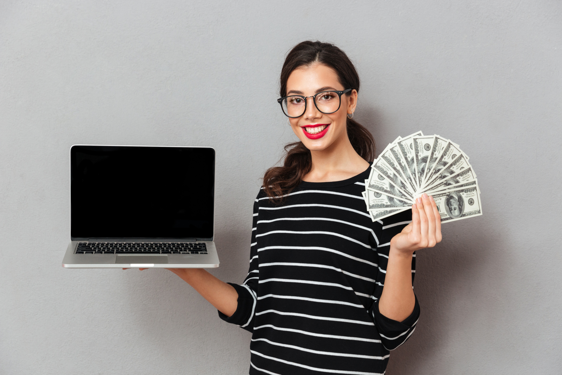 Woman holding dollar bills and a laptop symbolizing online business scams